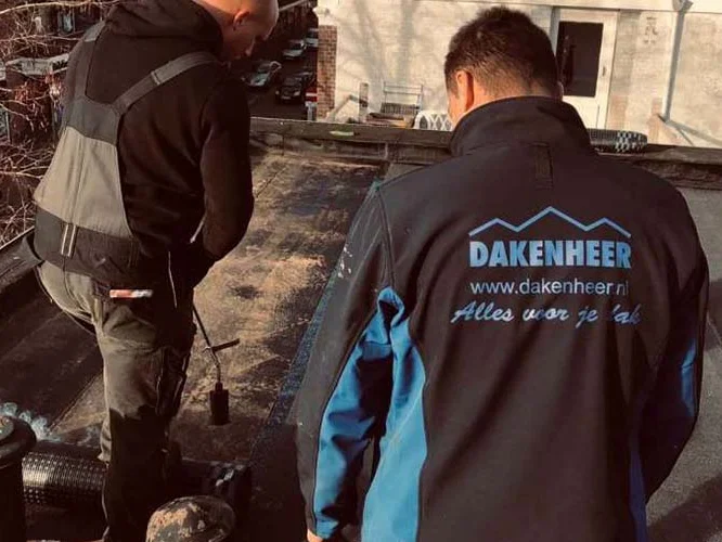 Twee dakdekkers bij een dakreparatie op een plat dak