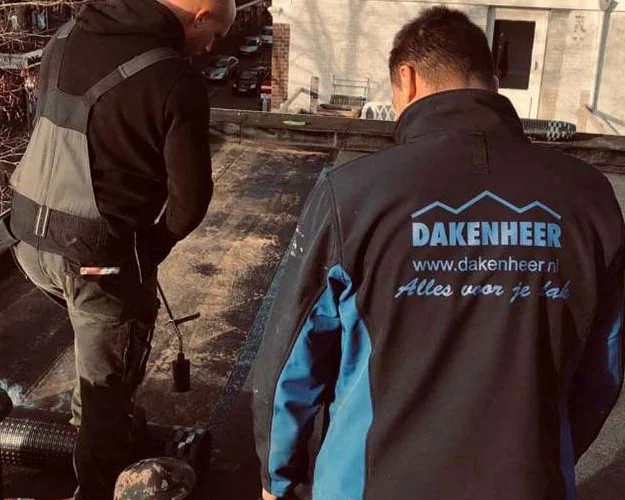 Twee dakdekkers bij een reparatie op een plat dak