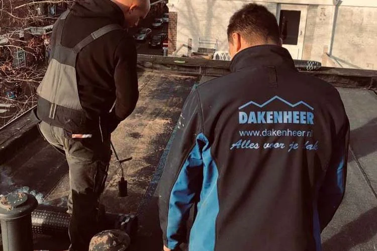 Twee dakdekkers bij een dakreparatie op een plat dak