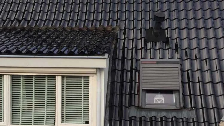 Nieuw gelegde donkere dakpannen met dakkapel