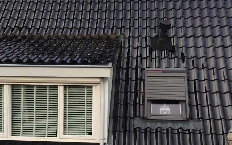 Nieuw gelegde donkere dakpannen met dakkapel
